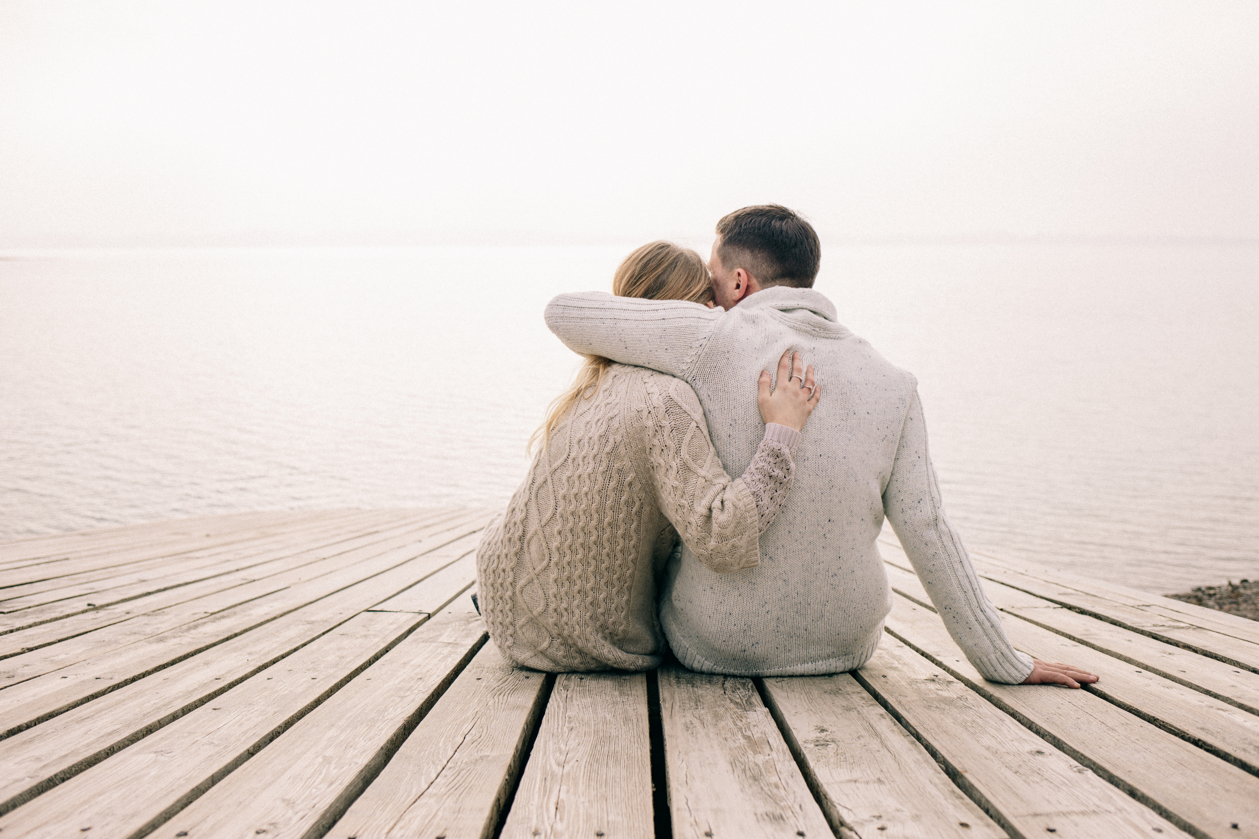 couple hugging on a pier couple hugging on a pier overlooking water