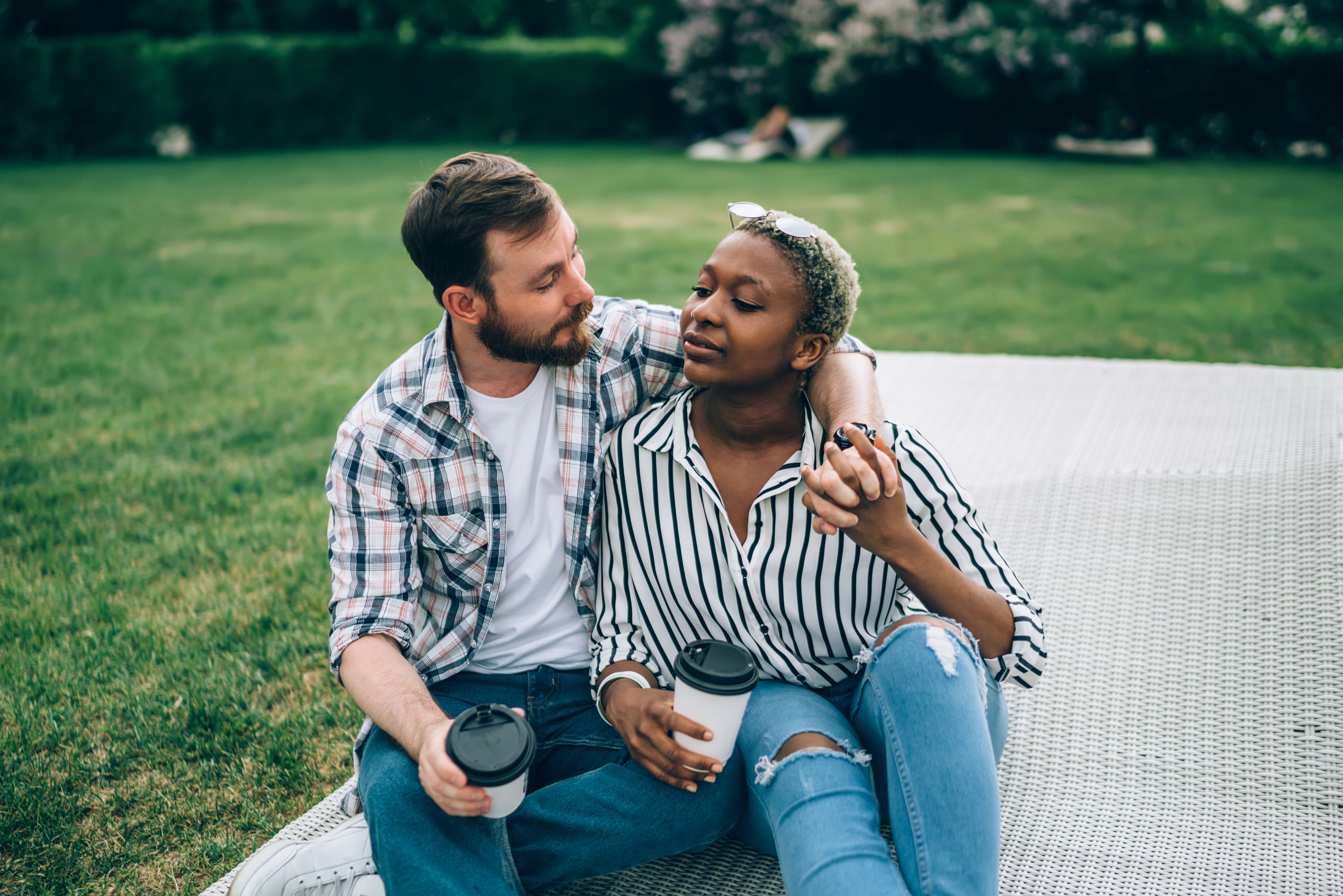 Couple in Park Multiracial couple drinking coffee on a picnic blanket