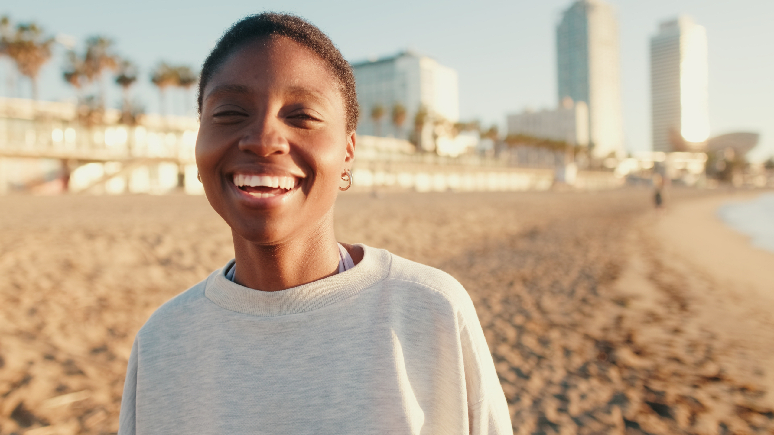 Young woman on beach Young woman with short hair walking on the beach and smiling